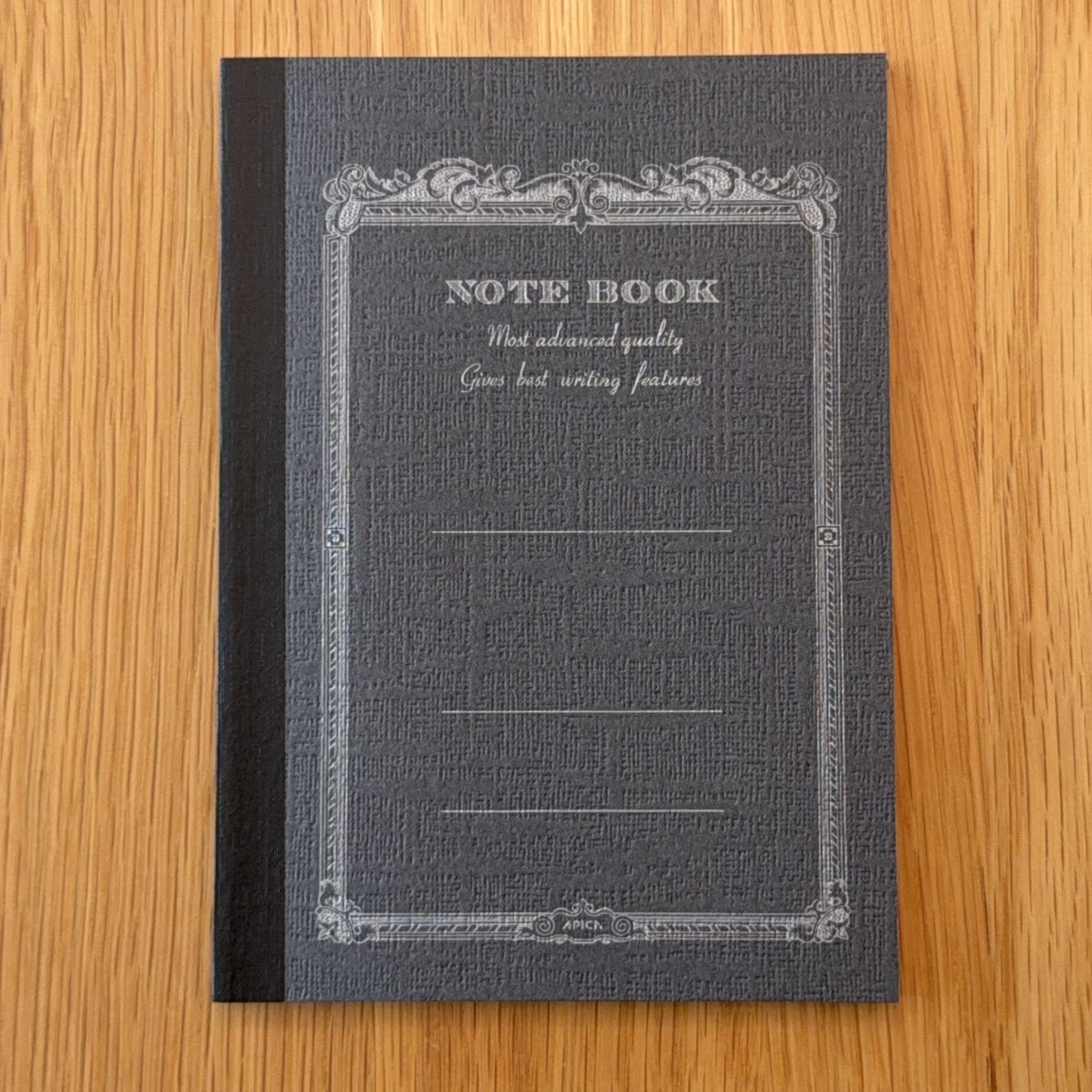 Apica CD Notebook A6 in Black, shown flat on a wooden surface