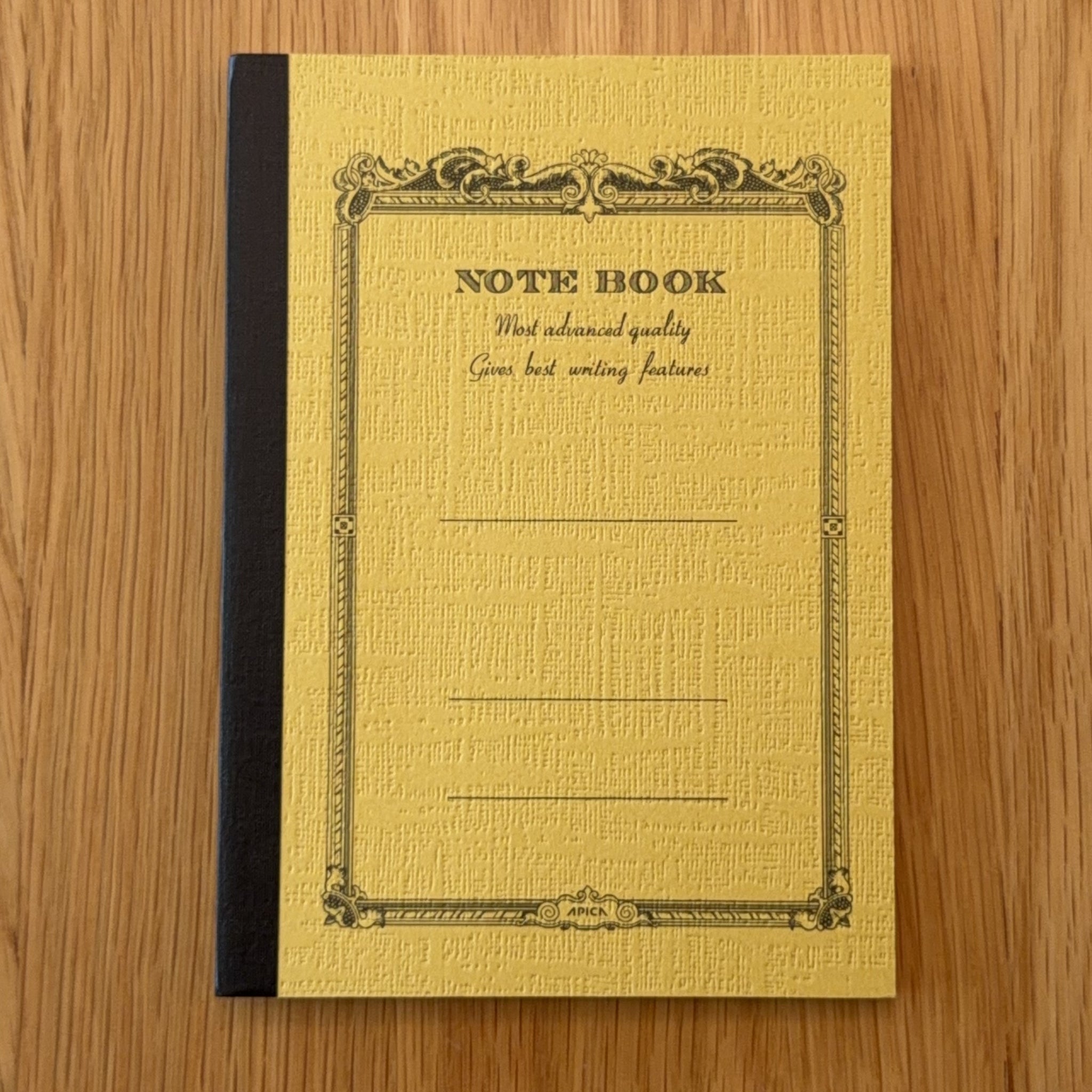 Apica CD Notebook A6 in Mustard, shown flat on a wooden surface