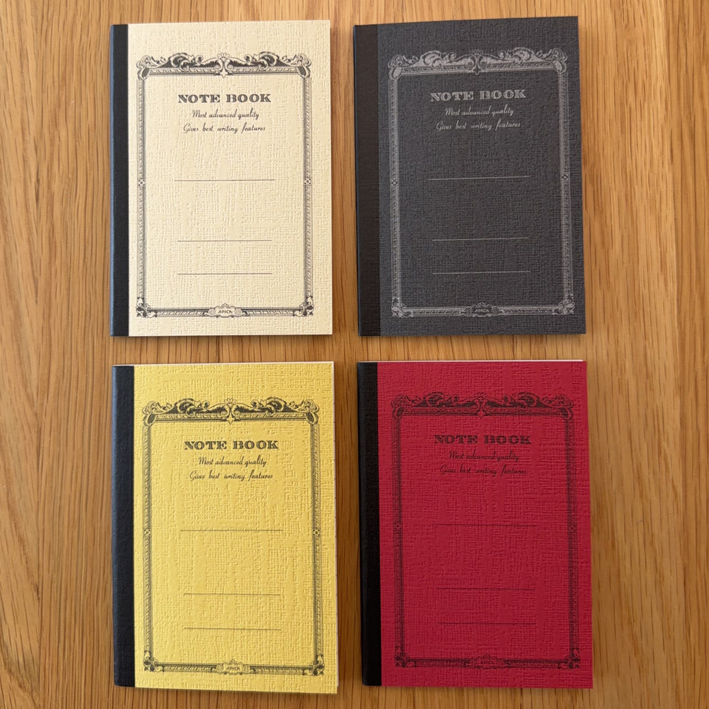 Four Apica CD Notebook A7 colors (Yellow, Black, Mustard, and Red) shown together