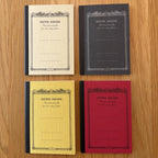 Four Apica CD Notebook A7 colors (Yellow, Black, Mustard, and Red) shown together