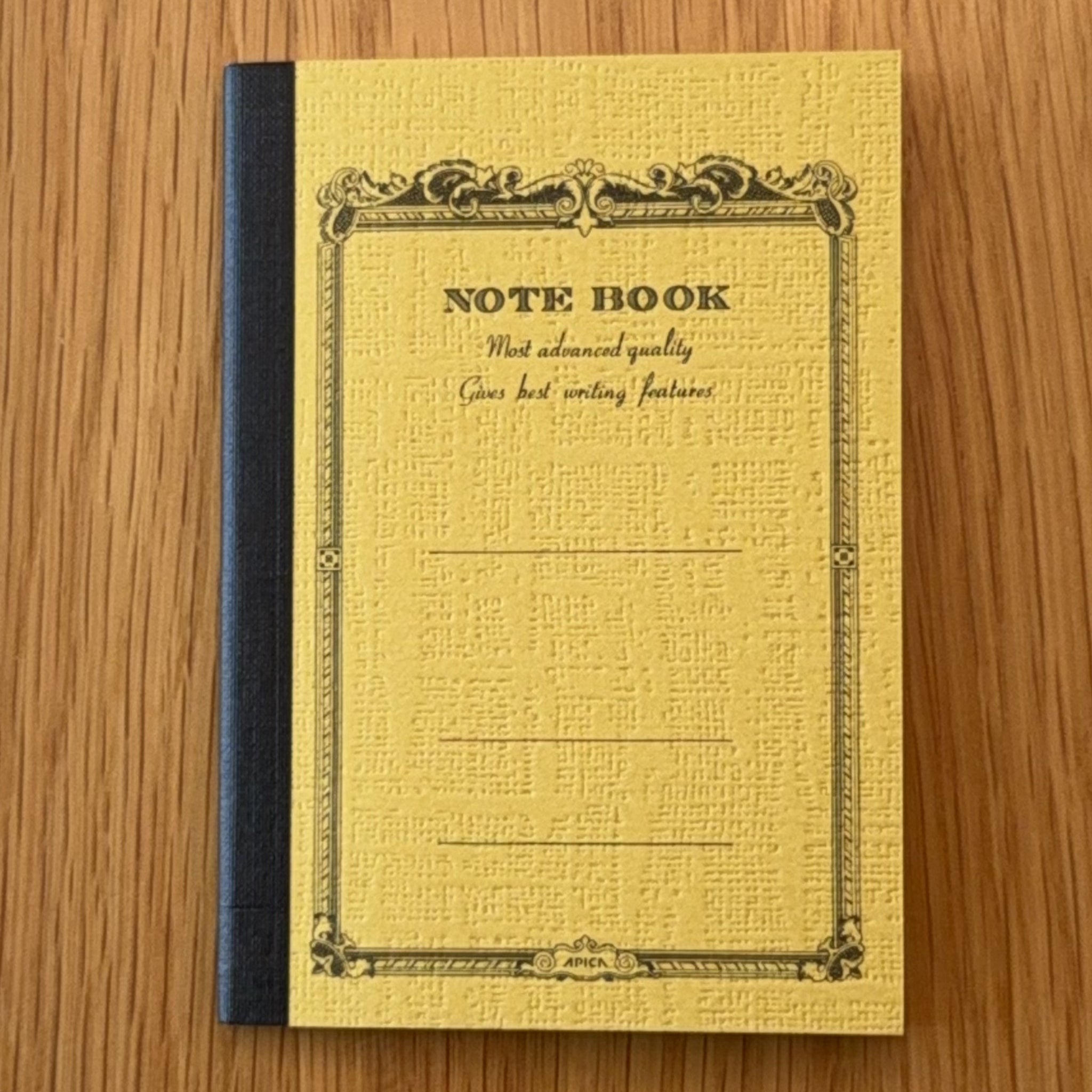 Apica CD Notebook A7 in Mustard, shown flat on a wooden surface