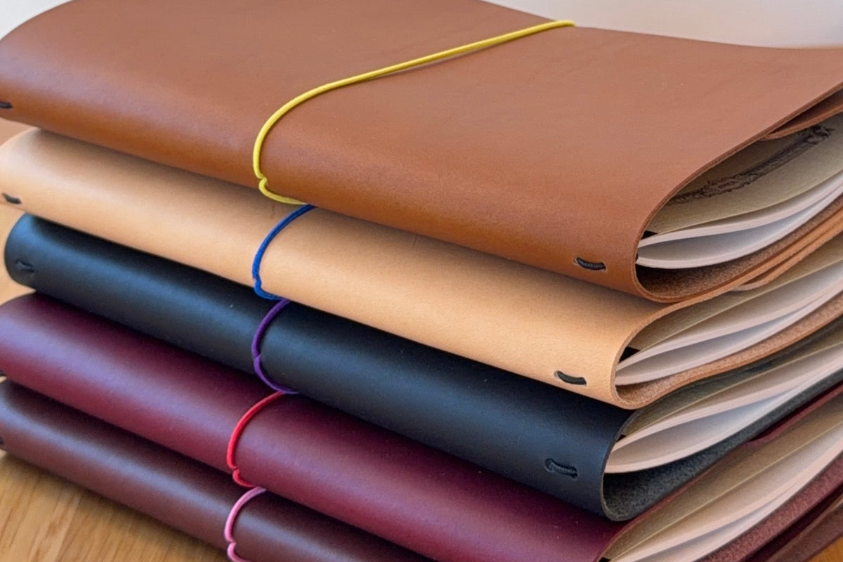 Five Journey covers stacked on top of each other in Cognac, Natural, Black, Bordeaux, and Tobacco.