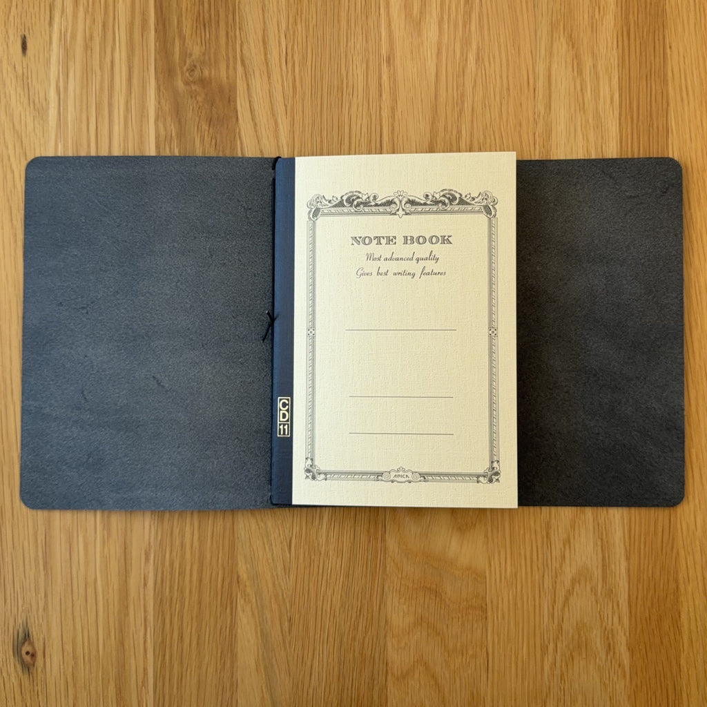 Journey A5 leather cover in Black, open to show the Apica CD notebook held inside by the elastic cord