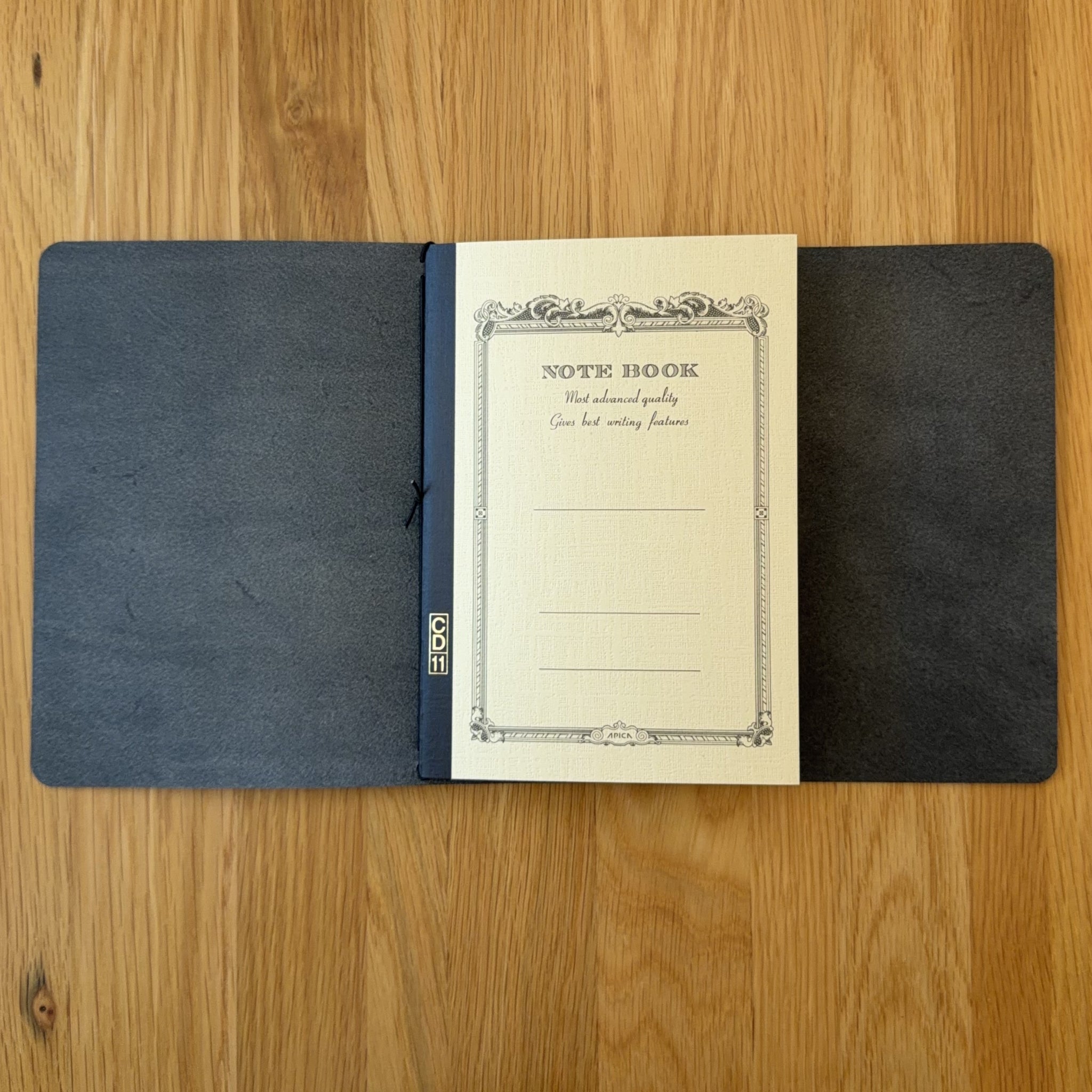 Journey A5 leather cover in Black, open to show the Apica CD notebook held inside by the elastic cord