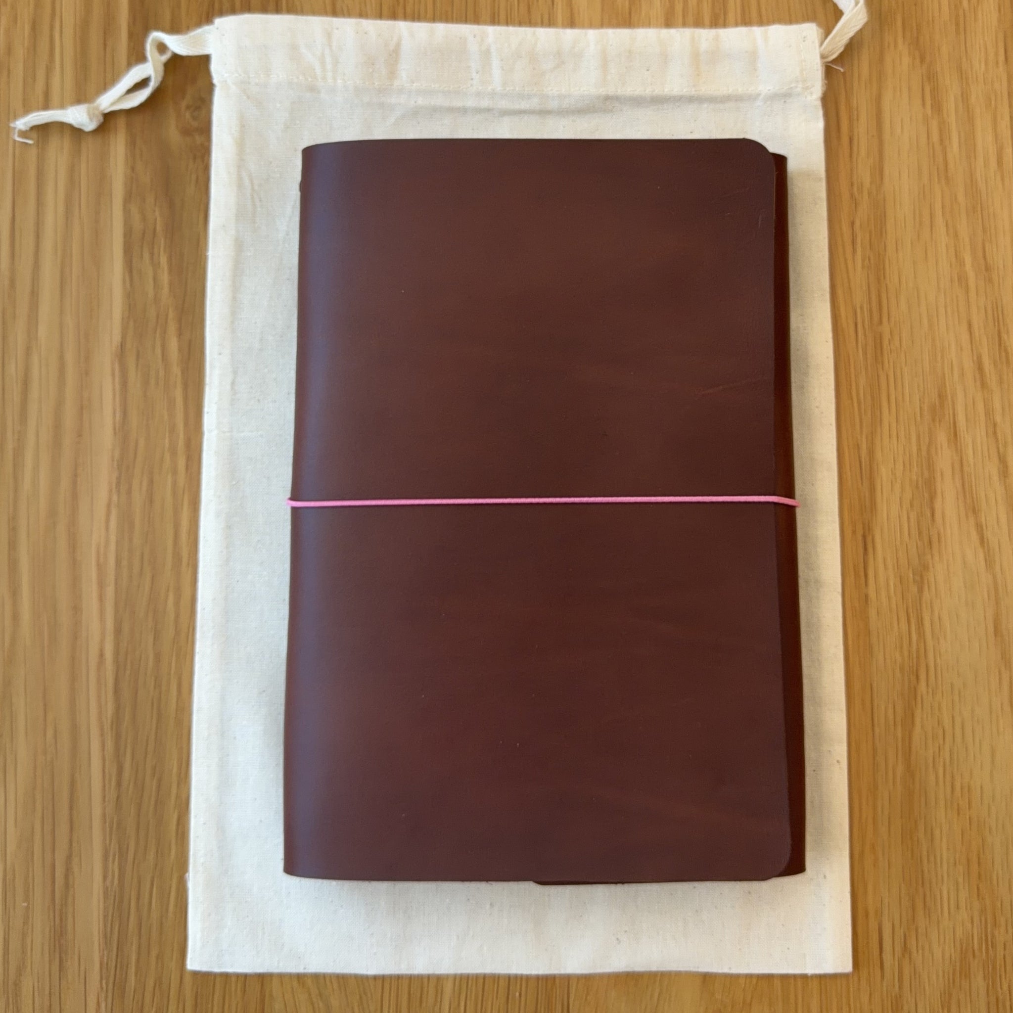 Journey A5 leather notebook cover in Tobacco, closed, resting on its Floramoon cotton dust bag