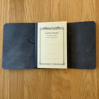 Journey A6 leather cover in Black, open to show the Apica CD notebook held inside by the elastic cord