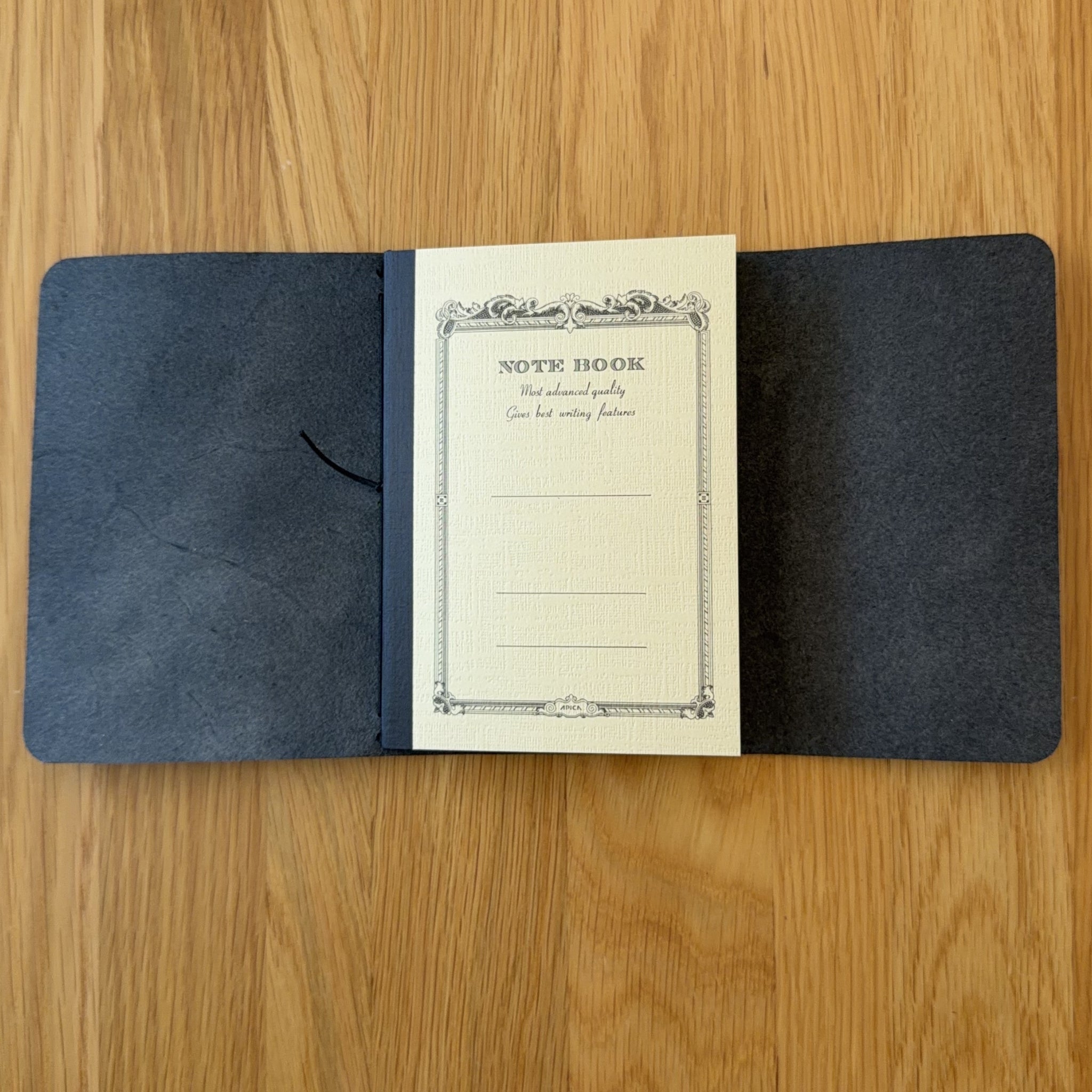 Journey A6 leather cover in Black, open to show the Apica CD notebook held inside by the elastic cord