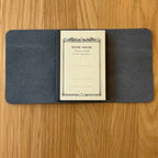 Journey A7 leather cover in Black, open to show the Apica CD notebook held inside by the elastic cord