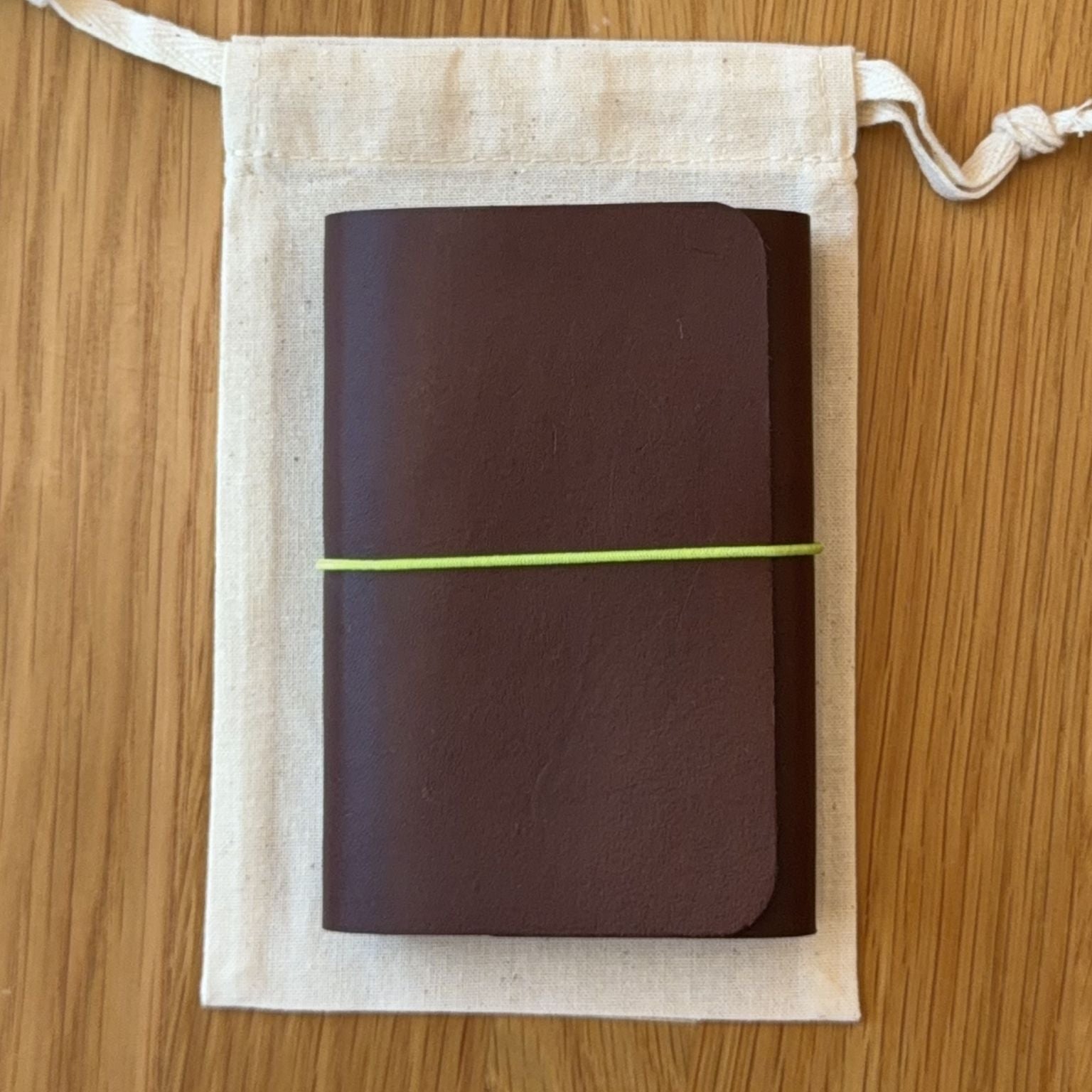 Journey A7 leather notebook cover in Tobacco, closed, resting on its Floramoon cotton dust bag