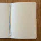 Midori MD Notebook A5 open to show the dot grid MD Paper and its bookmark string