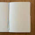 Midori MD Notebook A6 open to show the dot grid MD Paper and its bookmark string