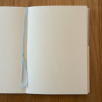 Midori MD Notebook A6 open to show the dot grid MD Paper and its bookmark string