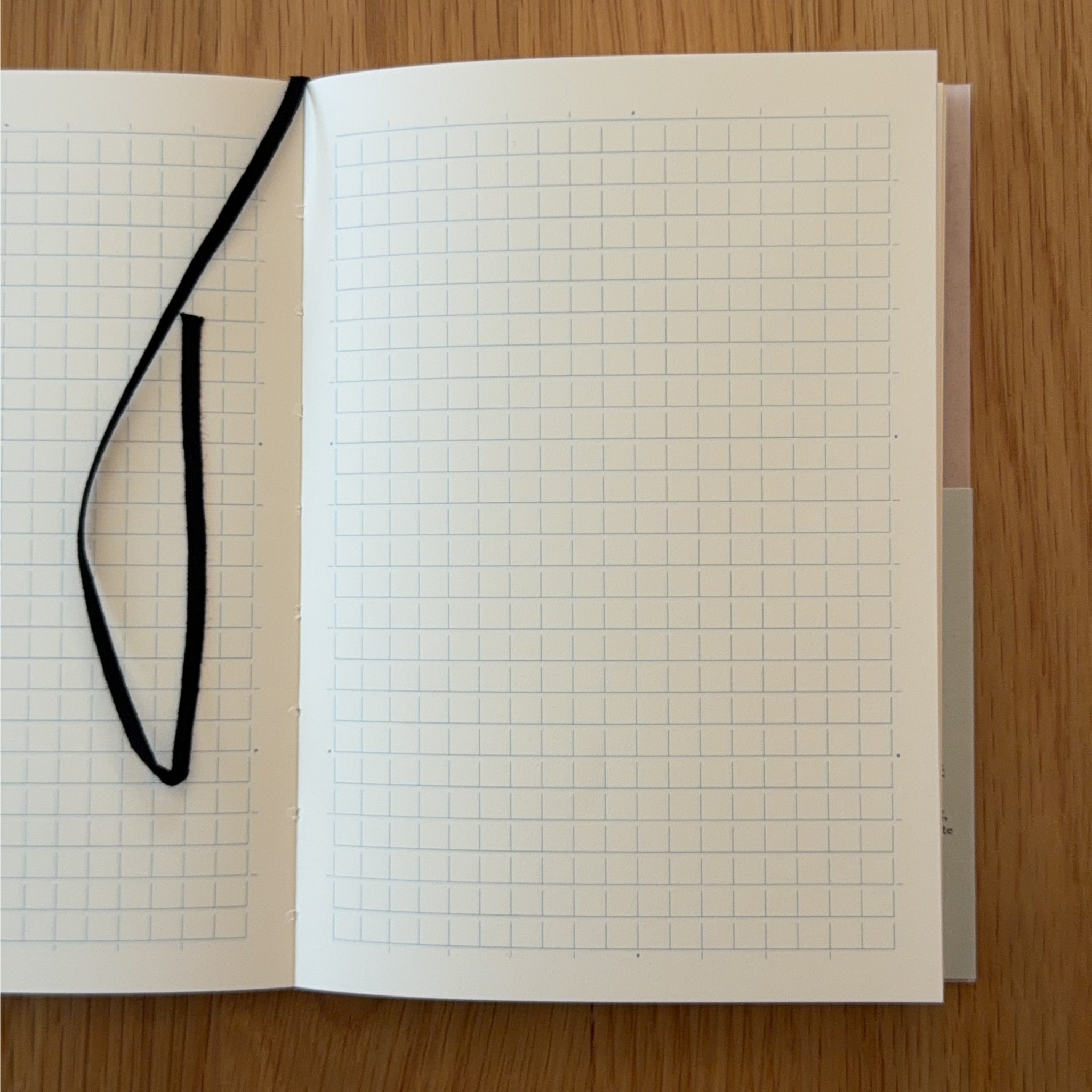 Midori MD Notebook A6 open to show the grid MD Paper and its bookmark string