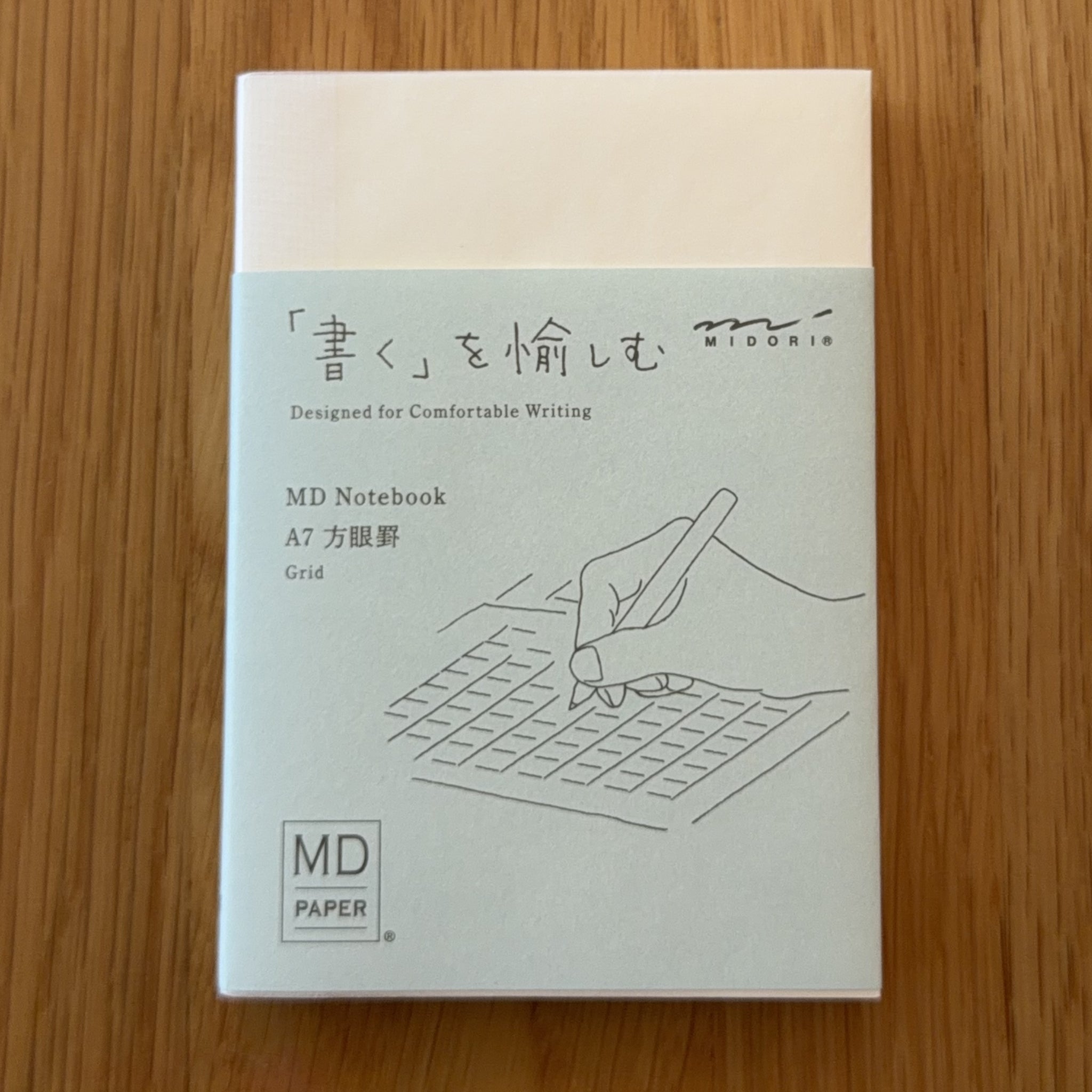 Midori MD Notebook A7 with glassine paper cover printed with a Grid ruling label and illustration