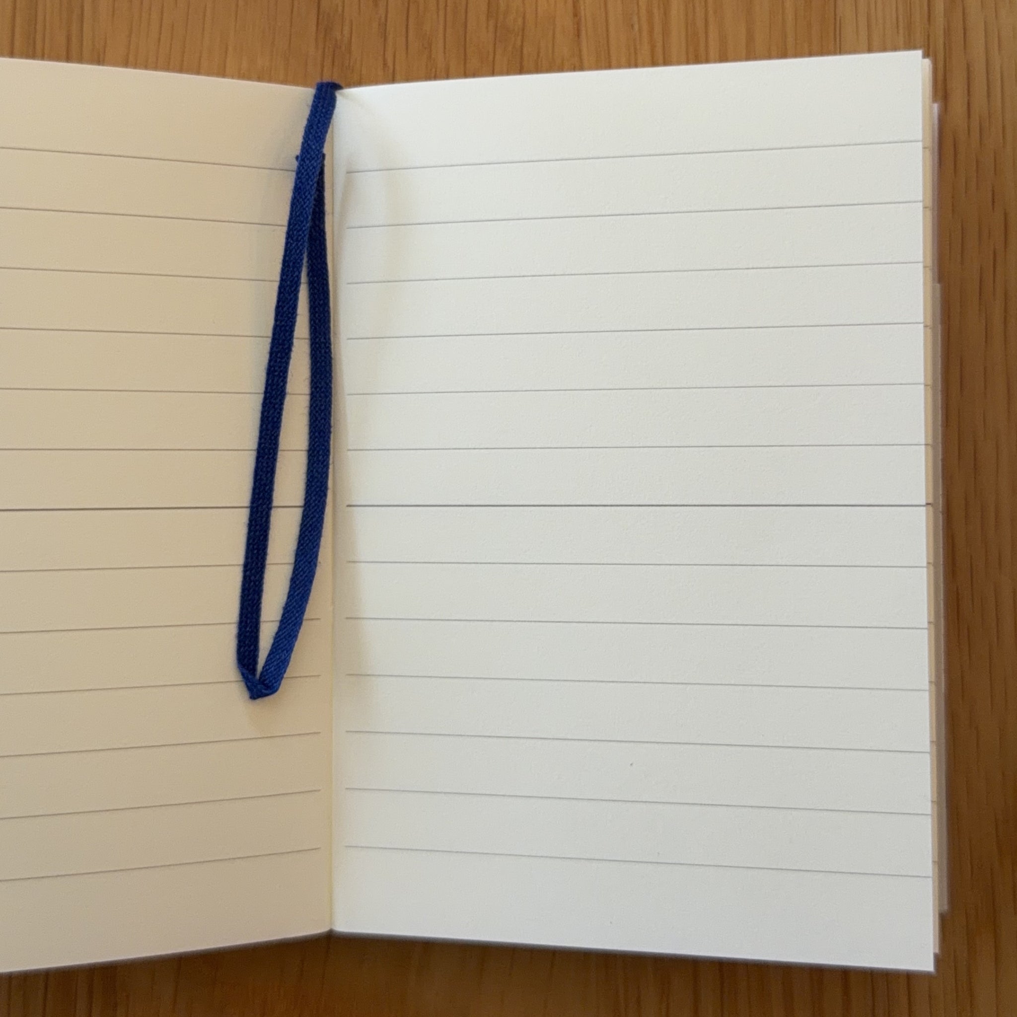 Midori MD Notebook A7 open to show the lined MD Paper and its bookmark string